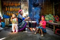 Ethnic mother preparing food against crying girl and baby indoors