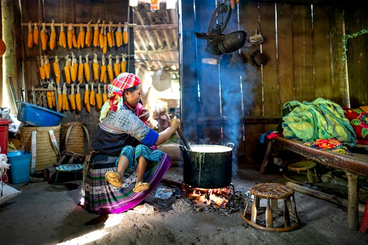 Ethnic Mother With Unrecognizable Daughter Stirring Food In Cauldron Indoors