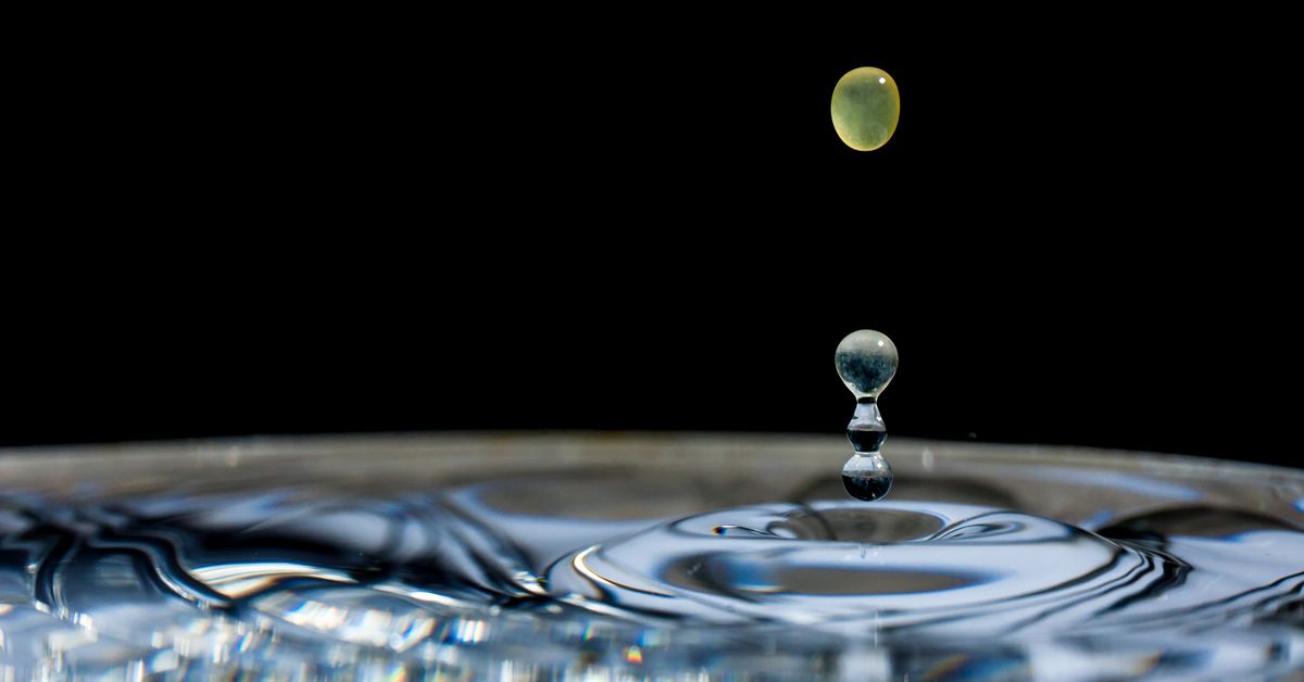 A droplet falling into dark water in close-up