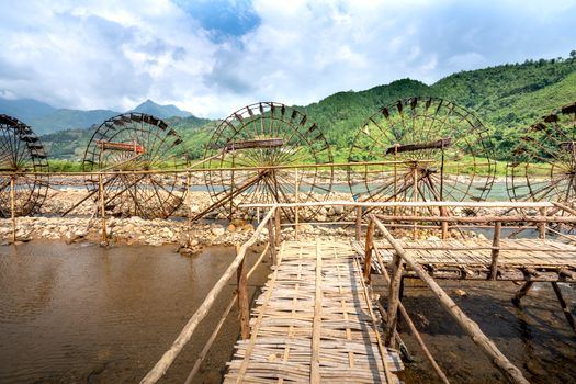 Water wheels against river and green mountains in countryside