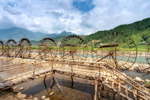 Water wheels on river between footbridge and ridges