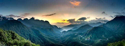 Magnificent mountains with wavy roads under cloudy sky at sunset