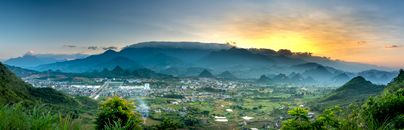 Misty mountains and village under colorful sky in evening