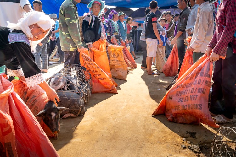 Crop Asian Sellers With Bags In Urban Market