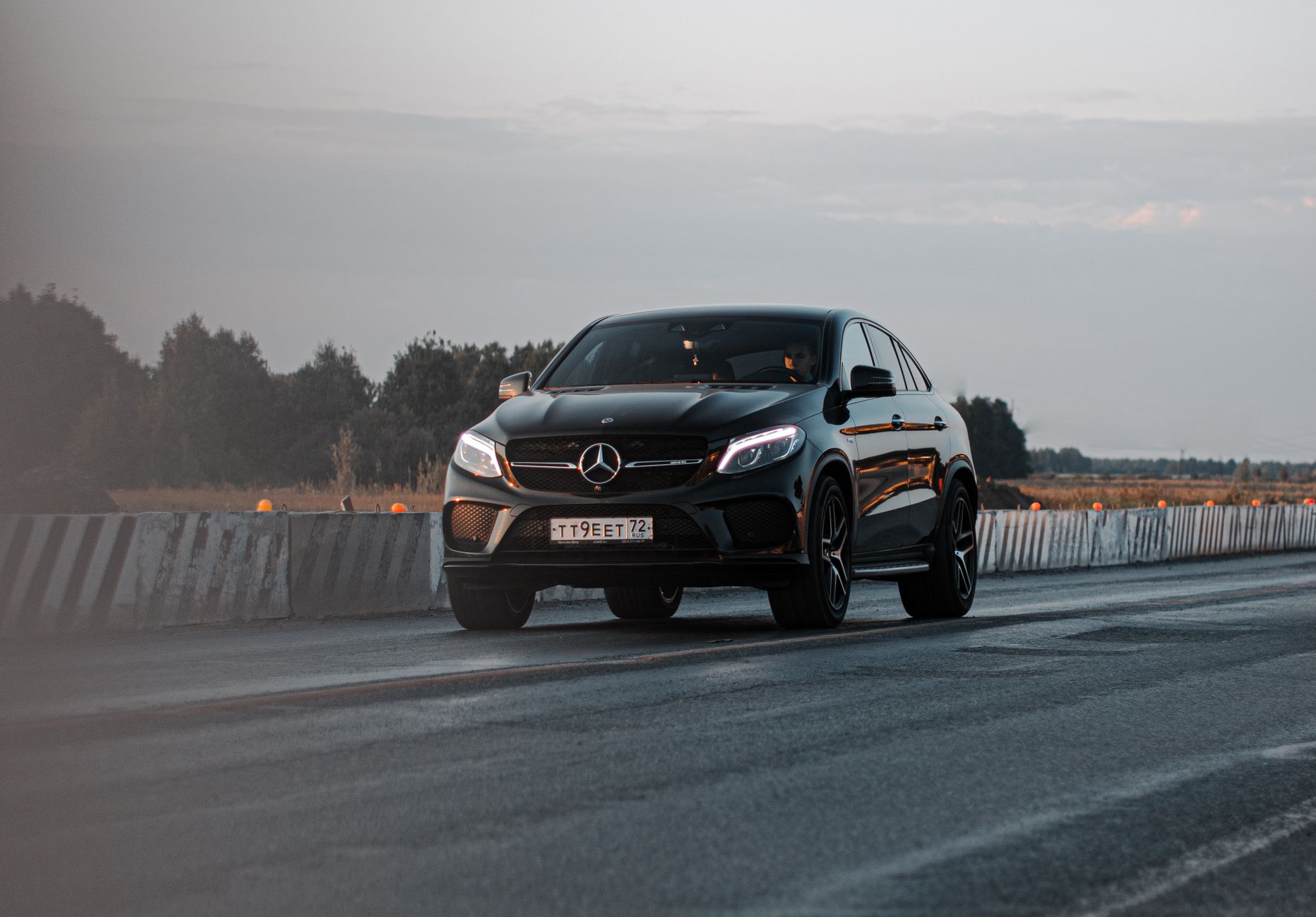 A sleek black Mercedes-Benz cruising on a highway during a serene day, showcasing elegance and performance.