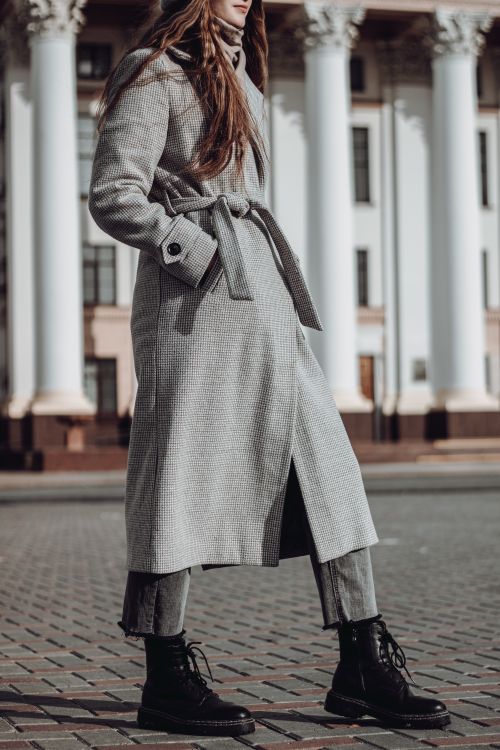 Free Fashionable woman in a long coat and boots standing outdoors, showcasing autumn style. Stock Photo