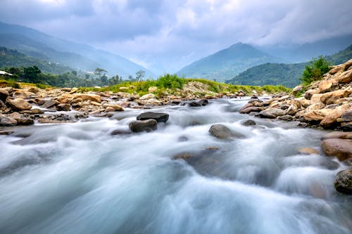 Free Flowing River Near Rocky Mountains Under a Cloudy Sky Stock Photo