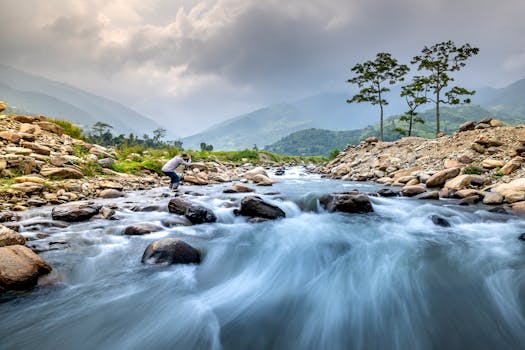 A picturesque river with long exposure flowing through rocky landscape under cloudy sky.