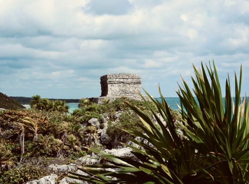 Free A scenic view of a Mayan ruin amidst lush greenery and ocean backdrop. Stock Photo