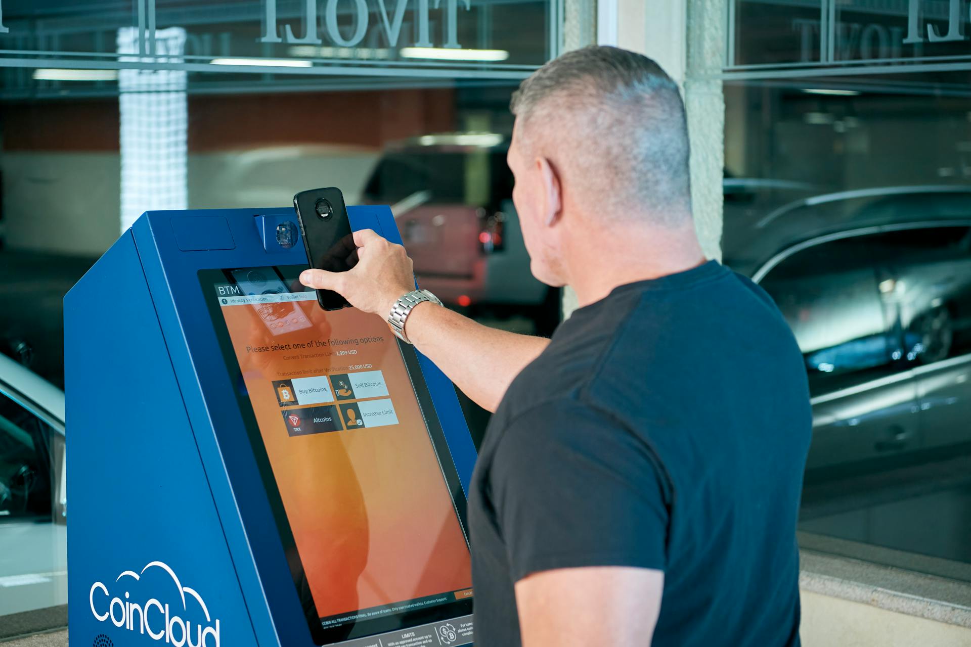 Man Placing his Phone on an ATM