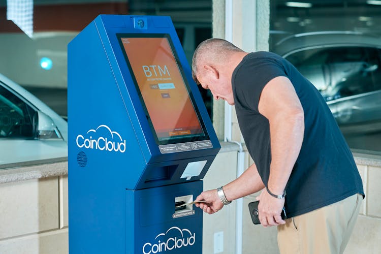 Man In Black Shirt Using An ATM