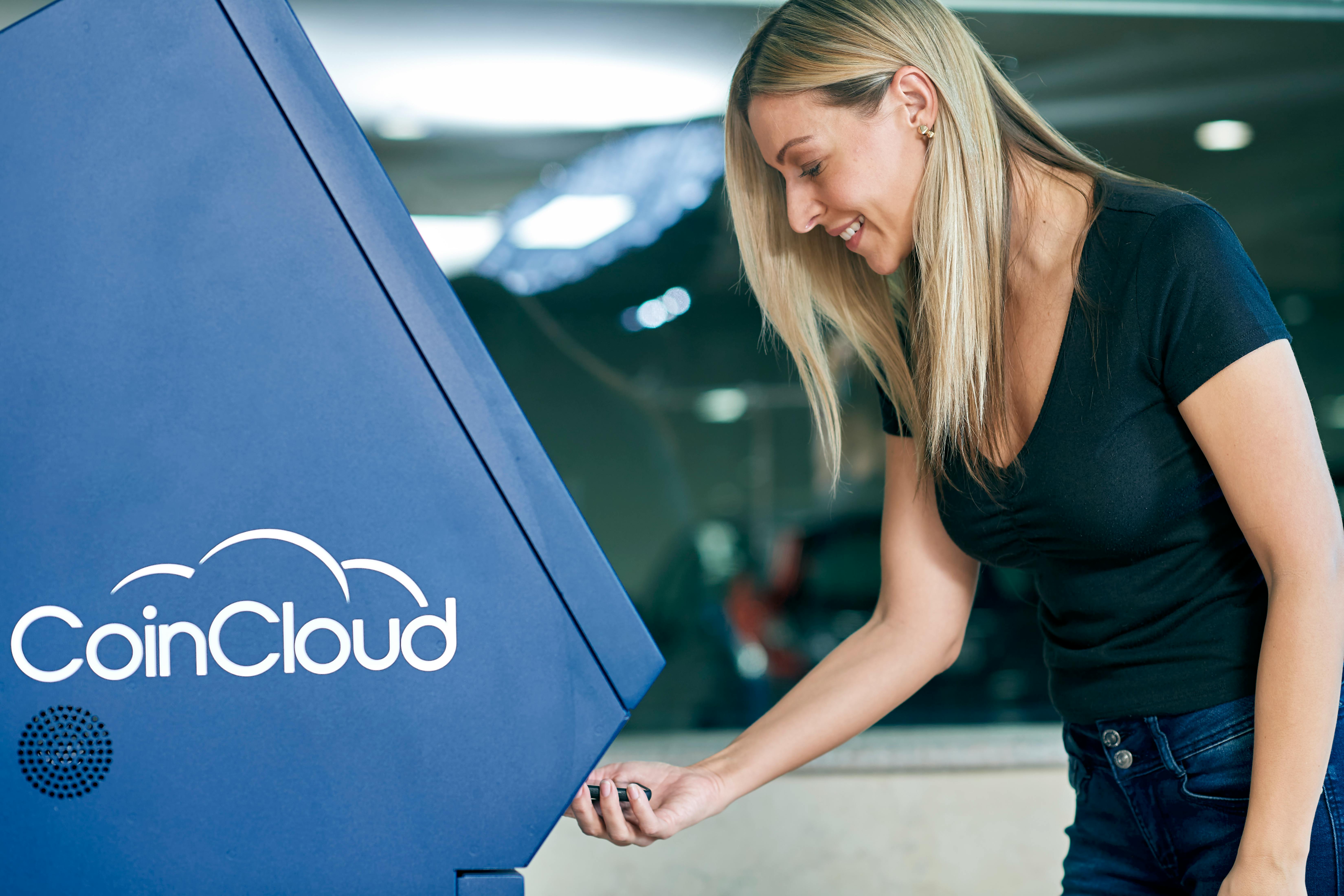 A woman uses a CoinCloud ATM indoors, highlighting modern digital finance.