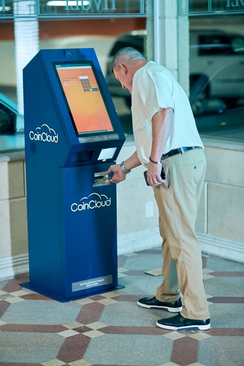 Free Adult man using Coin Cloud ATM for digital currency transaction indoors. Stock Photo