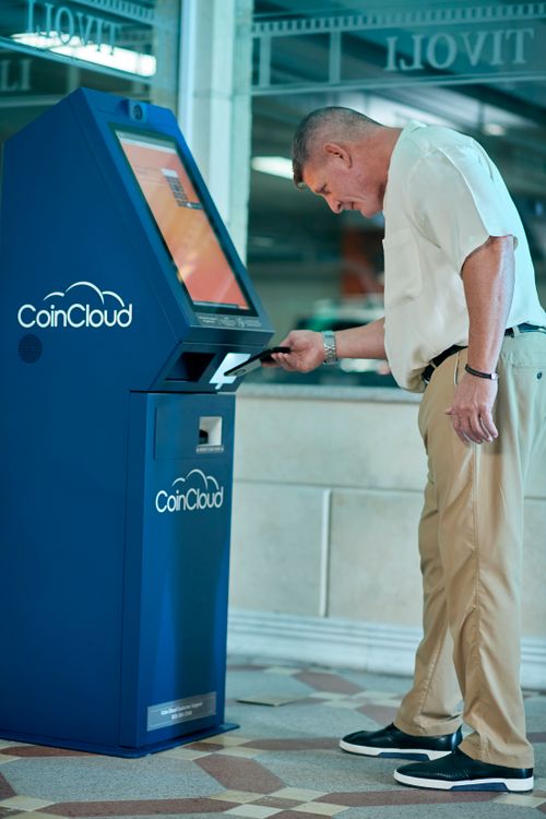 Free Adult man using a Coin Cloud Bitcoin ATM indoors for cryptocurrency transaction. Stock Photo