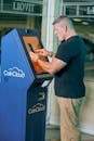Man in Black Crew Neck T-shirt using an ATM