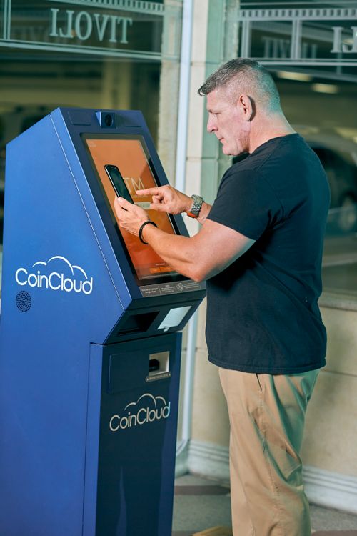 Free Adult man interacting with a CoinCloud cryptocurrency ATM in a city environment. Stock Photo