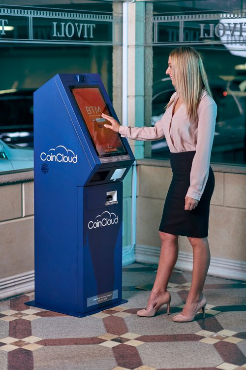 Free A businesswoman interacts with a CoinCloud cryptocurrency ATM indoors. Stock Photo