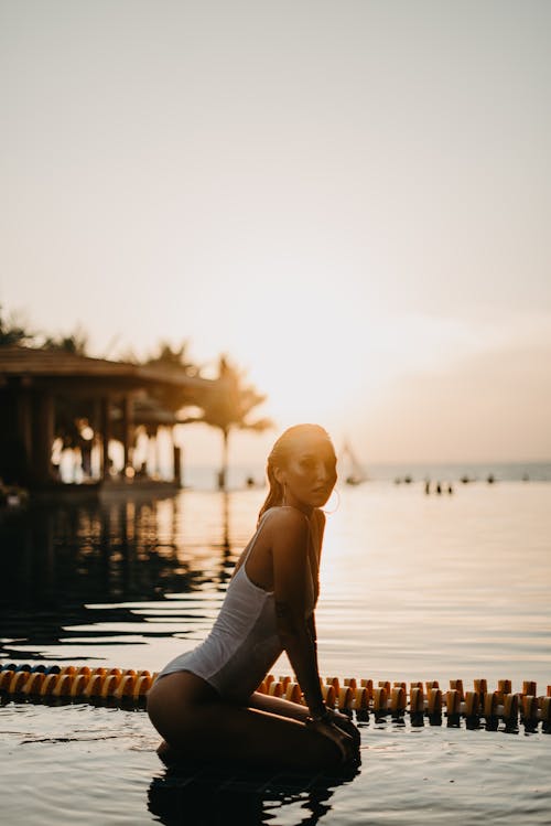 Woman in Black Tank Top Standing on Dock during Sunset