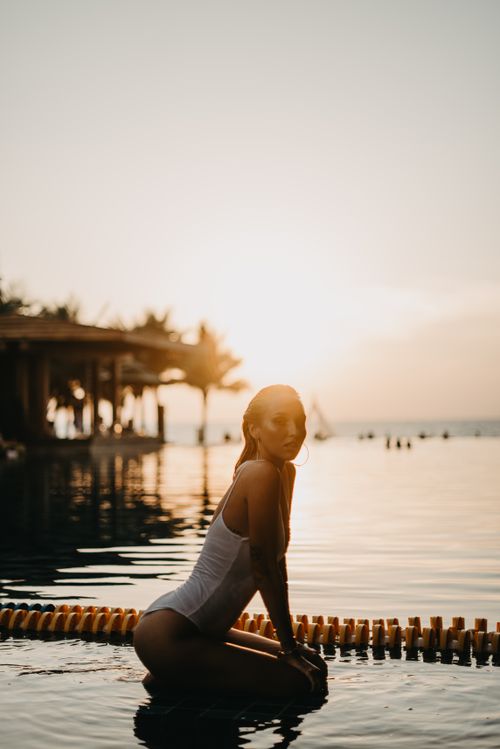 Free Woman enjoying a tranquil moment by the pool in Bali during sunset. Stock Photo
