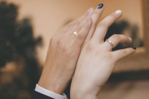 Free A close-up view of a couple's hands adorned with wedding rings, expressing love. Stock Photo