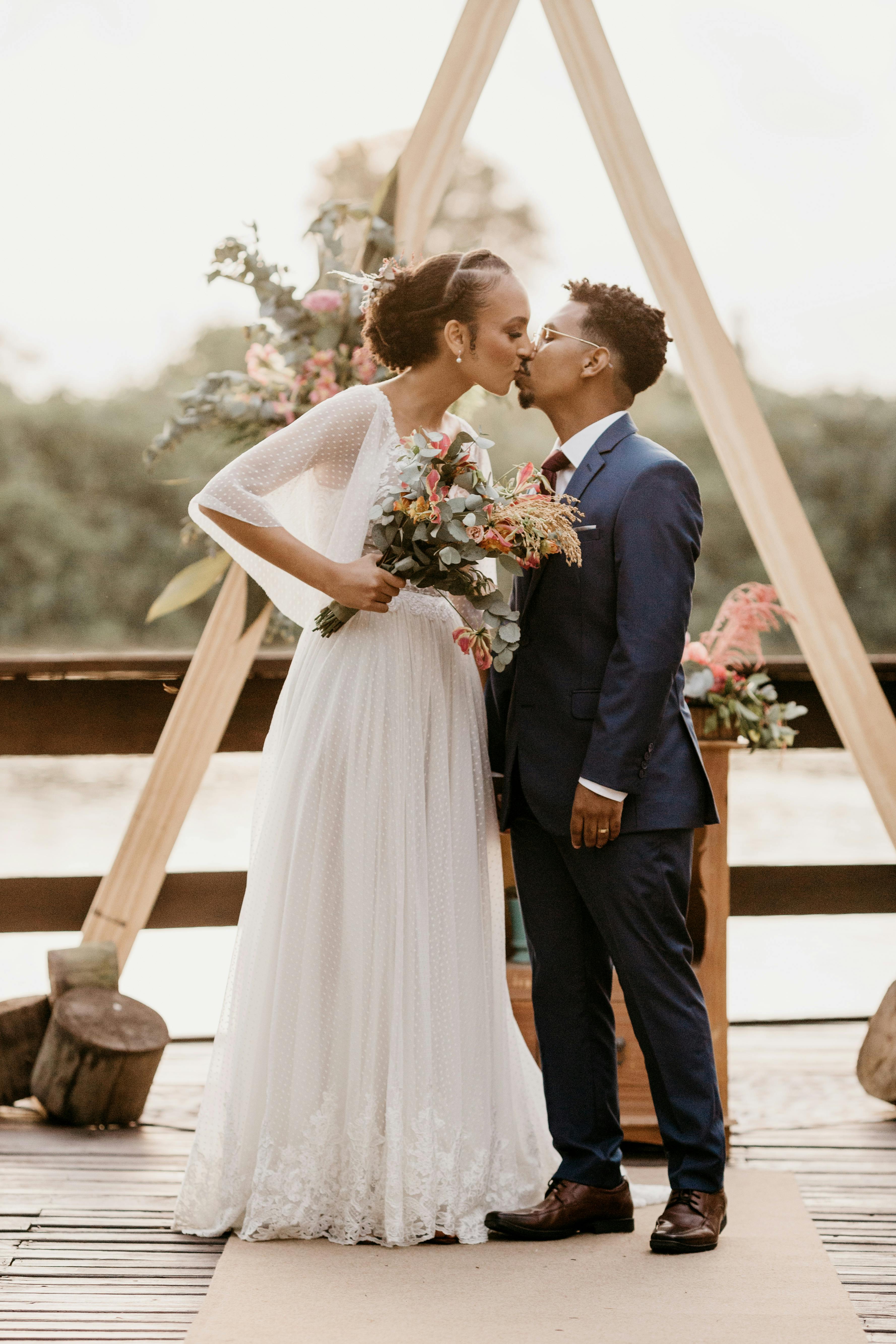 diverse newlywed couple kissing on wooden terrace