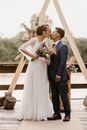 Diverse newlywed couple kissing on wooden terrace