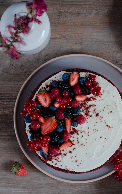 Free Top view of a red velvet cake decorated with fresh mixed berries on a wooden table. Stock Photo
