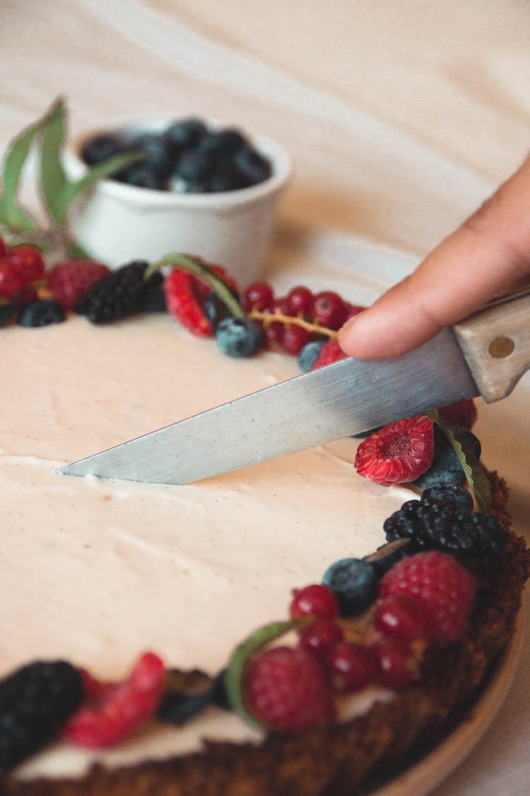 Close-Up Of A Person Cutting A Tart 