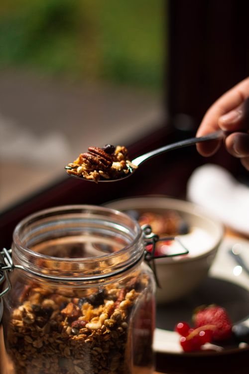 Free A spoonful of granola being lifted from a jar, showcasing a healthy breakfast option. Stock Photo