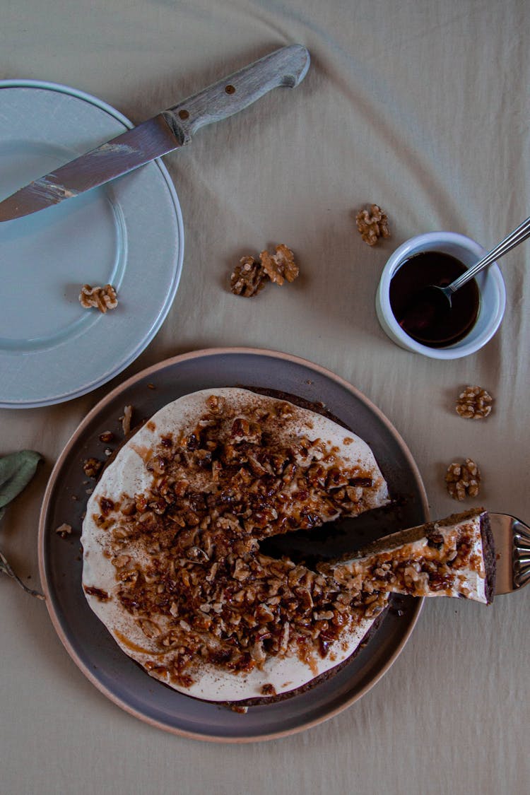 A Round Cake With Walnuts Toppings On Ceramic Plate