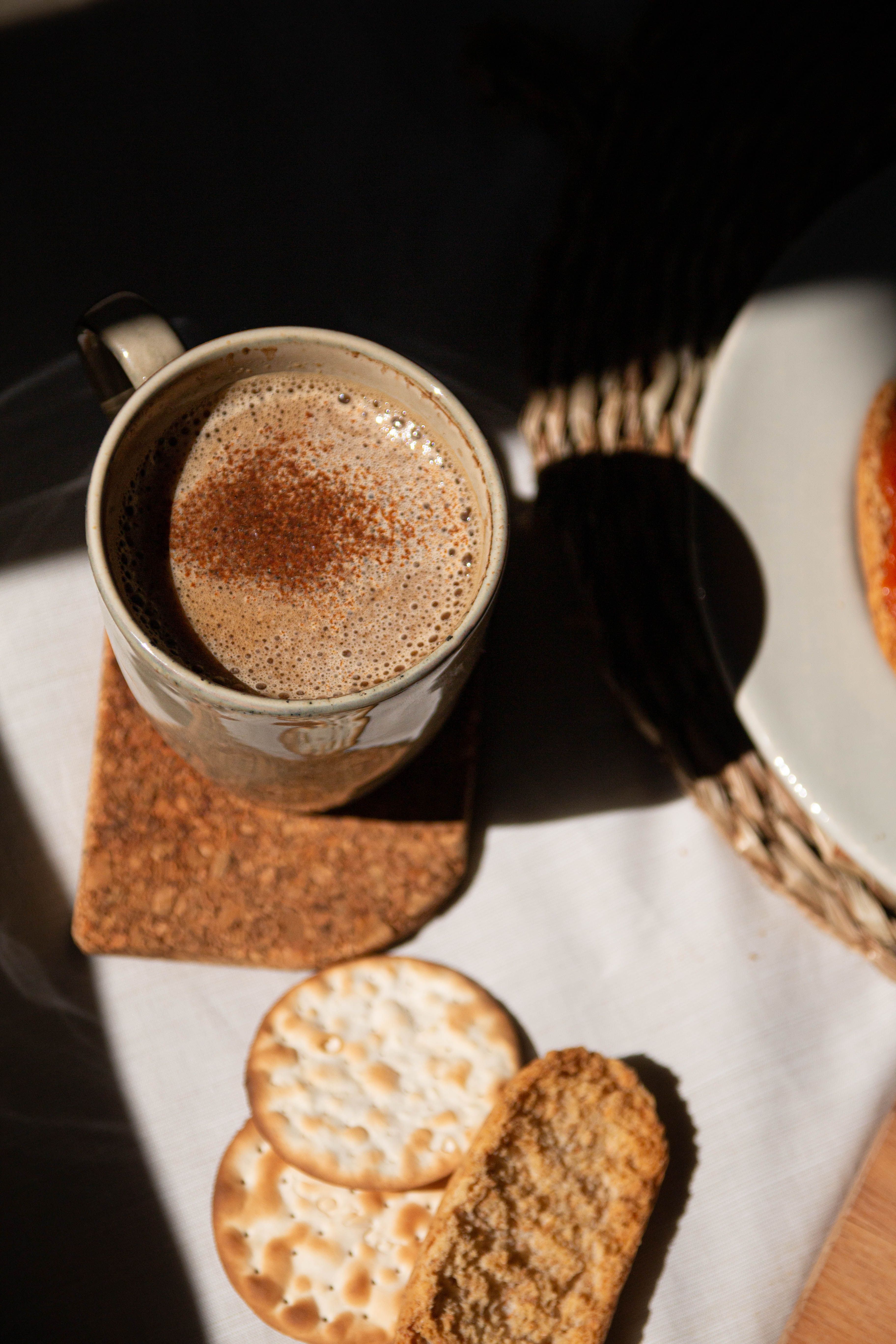 Cozy setup of coffee and crackers with warm sunlight and shadows.