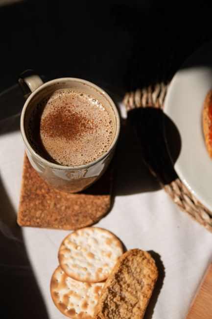 Cozy setup of coffee and crackers with warm sunlight and shadows.