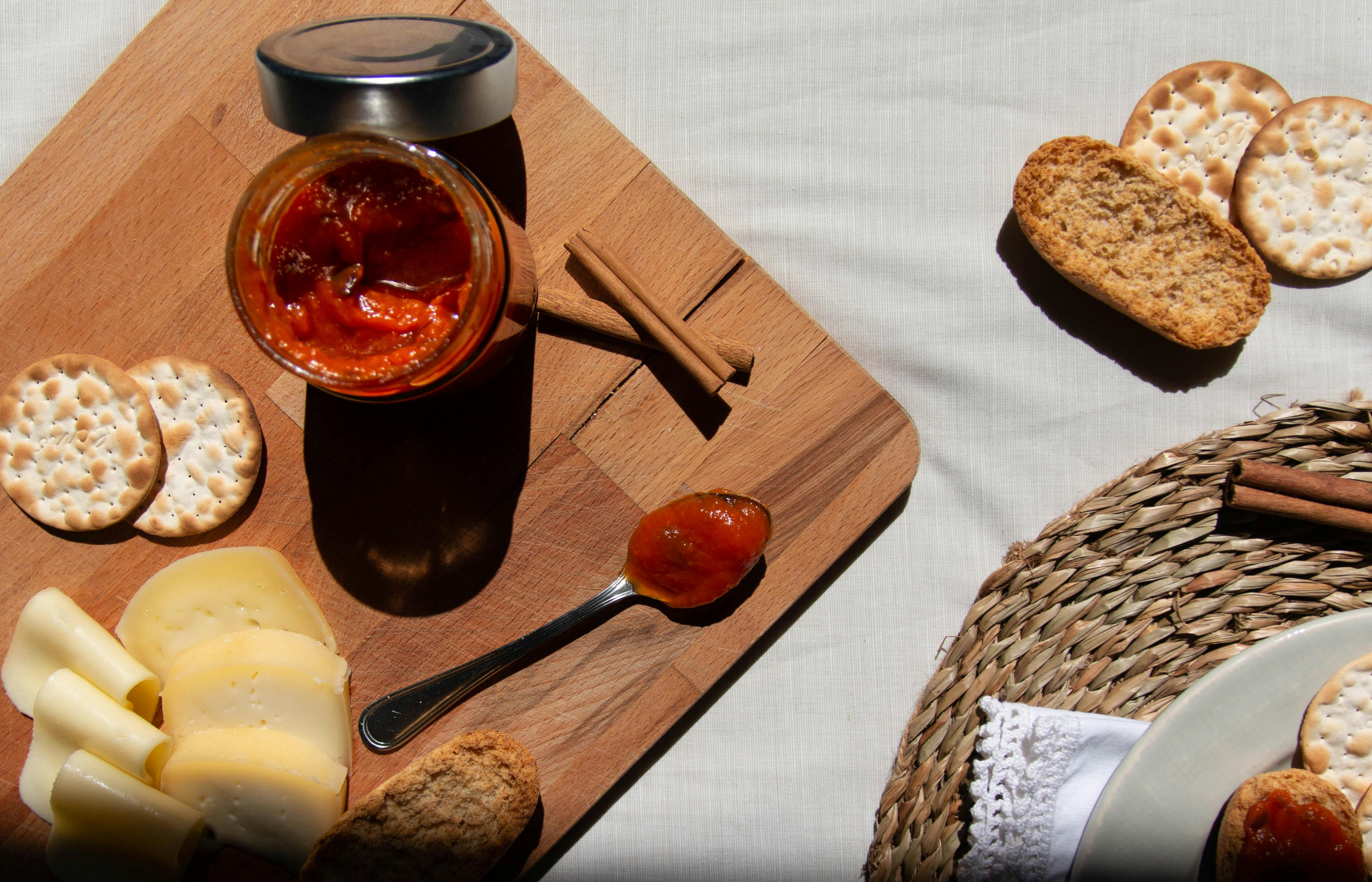 red sauce in a glass jar and on a spoon on a wooden board