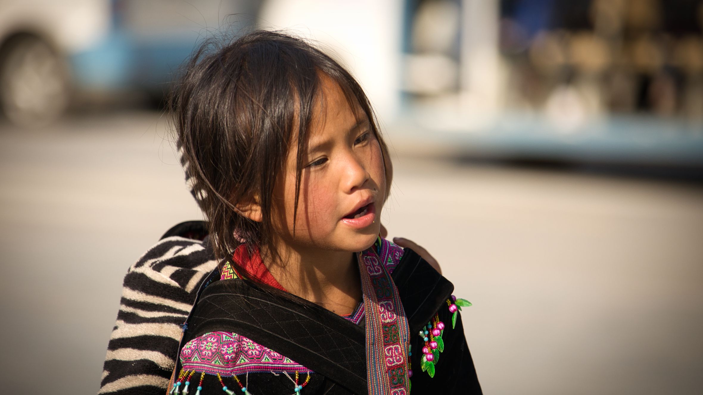 A young Hmong girl in traditional attire captured outdoors in LΓ o Cai, Vietnam.