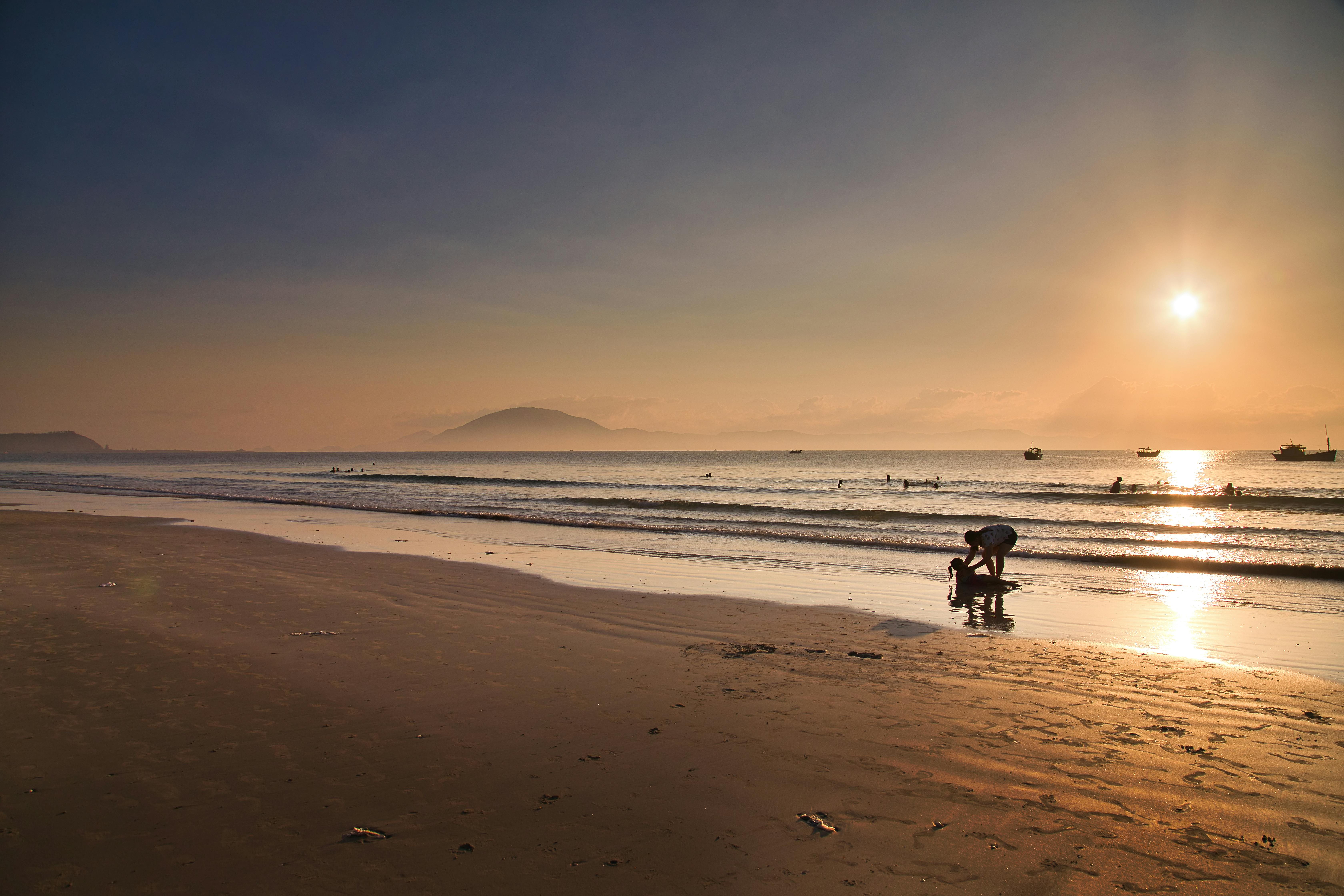 A serene evening on the beach at Ninh Hòa, Vietnam, with people enjoying the sunset and leisure activities.