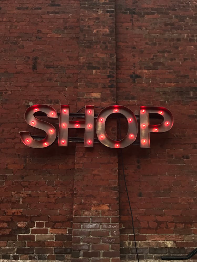 Metal Signage With Red Lights On A Brick Wall