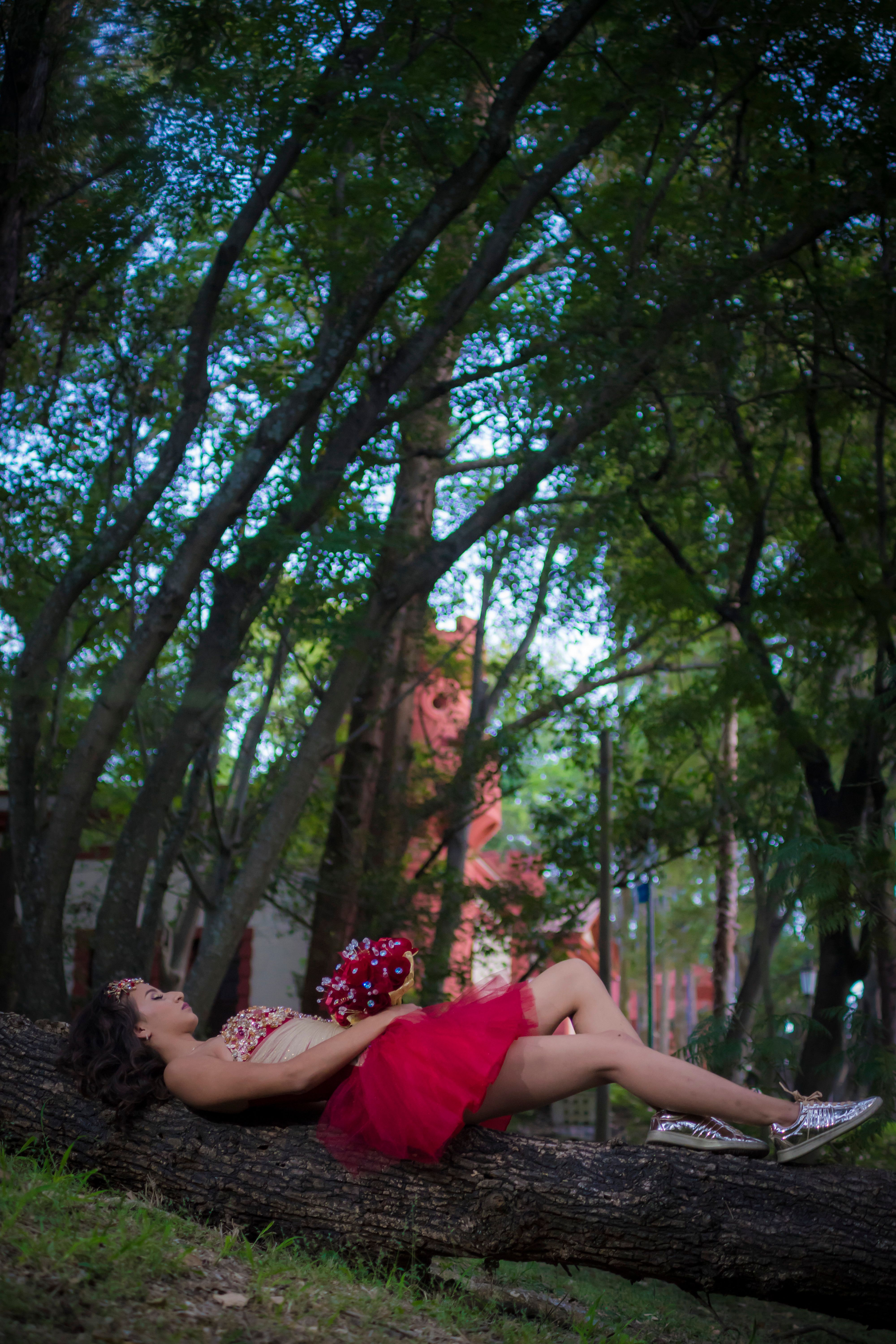A Woman Wearing a Red Dress Leaning on a Tree · Free Stock Photo