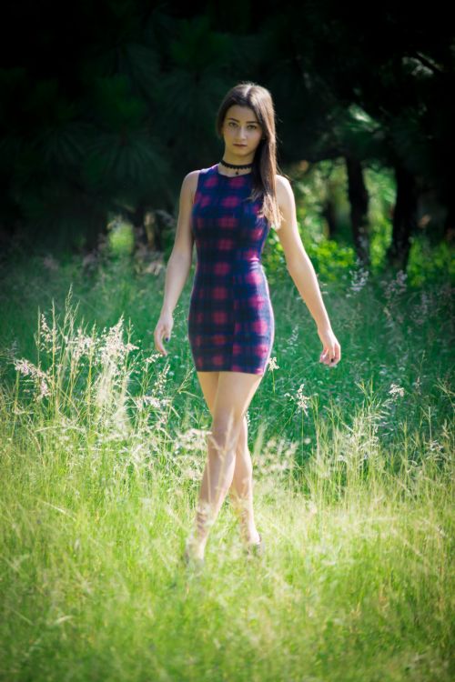 Free Stylish woman walking through a grassy field on a sunny day. Stock Photo