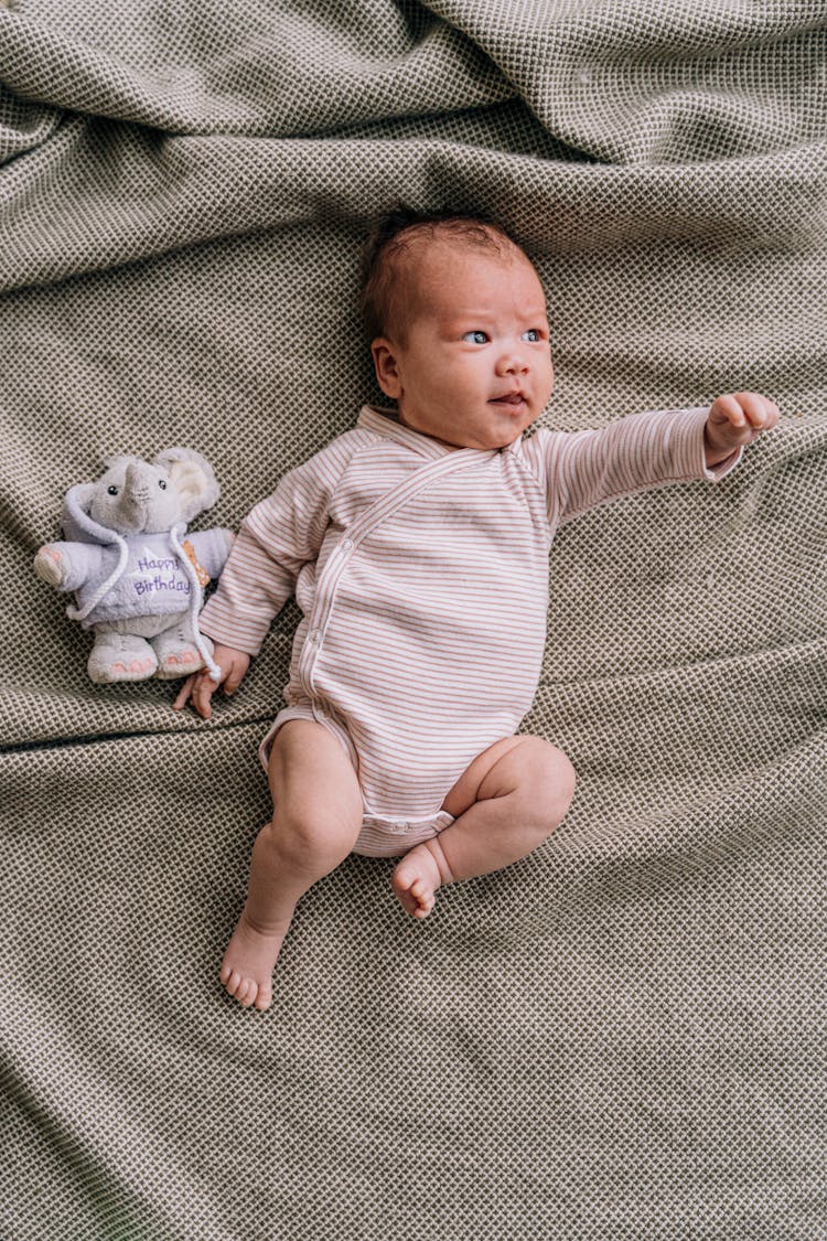 A Cute Baby In A Striped Onesie