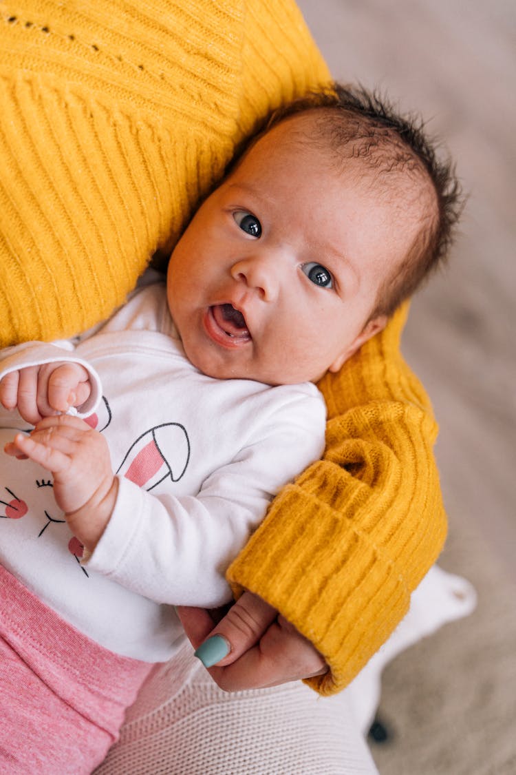 Woman In Yellow Long Sleeves Carrying A Baby