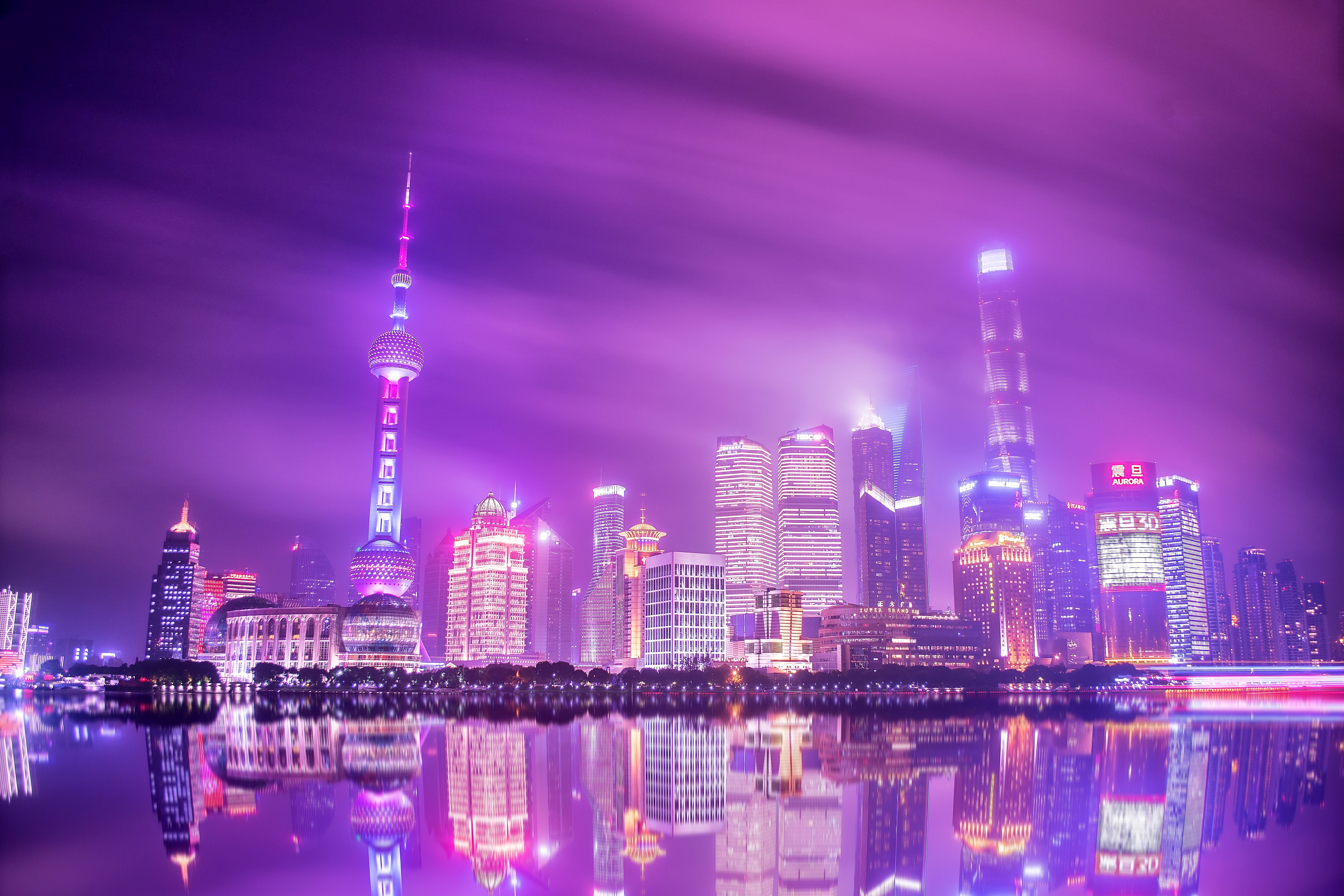 Stunning night view of Shanghai's skyline reflecting on water under a vibrant, colorful sky.