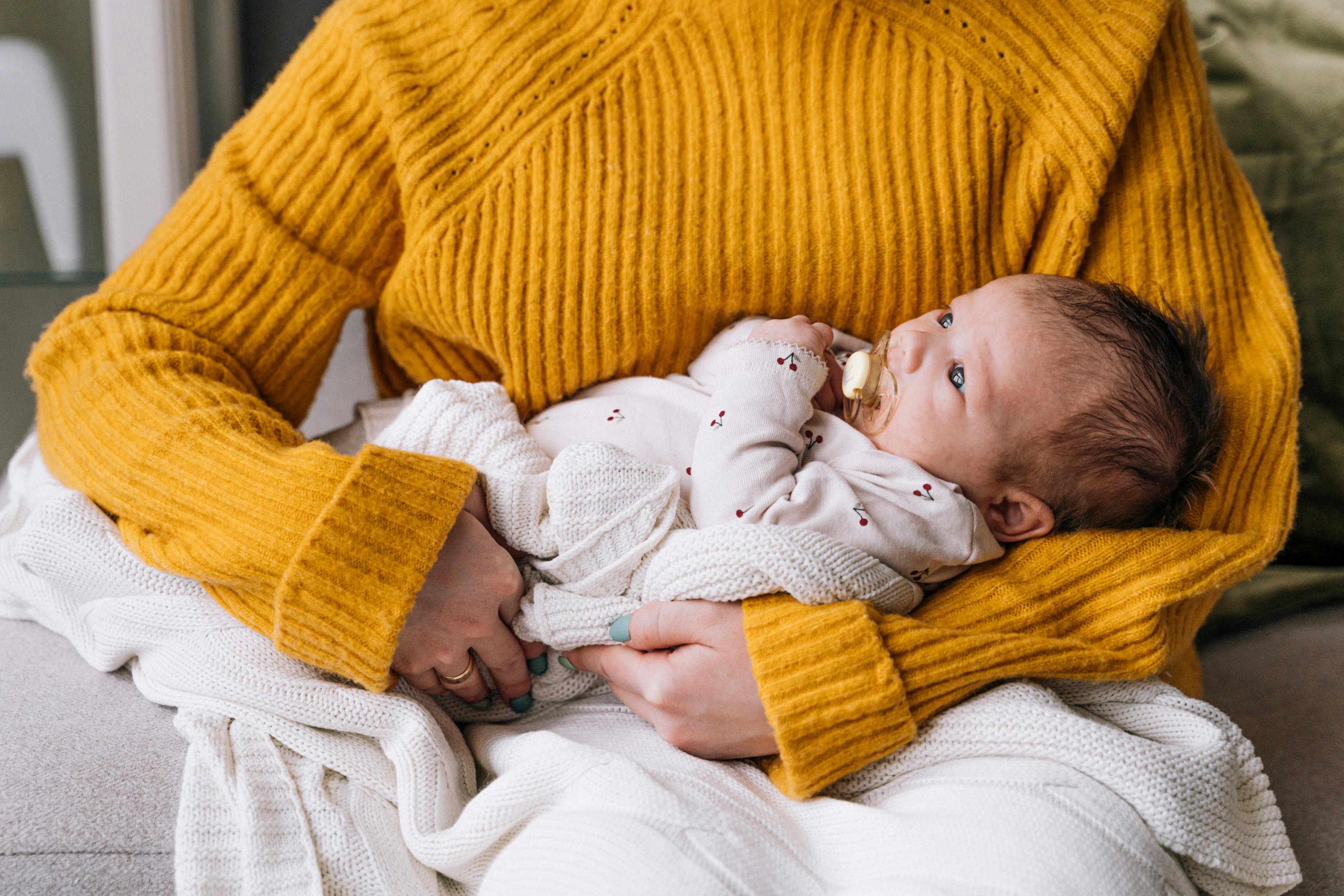 baby wearing pink long sleeves on a woman s arms