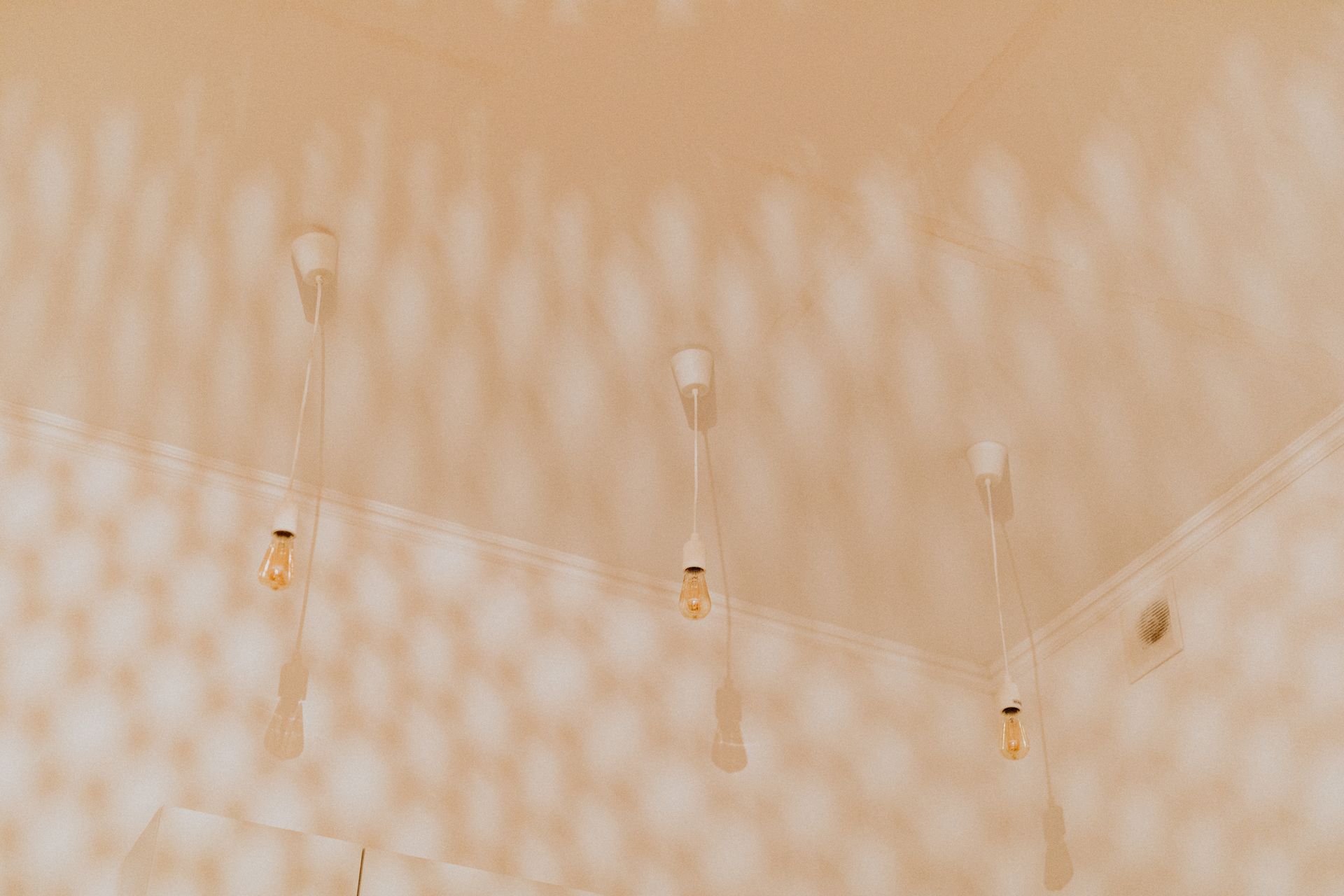 Minimalist ceiling featuring multiple hanging light bulbs creating intricate shadow patterns.