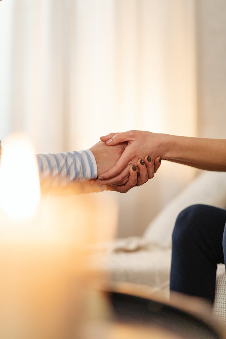 Hands Holding In Compassion And Blurred Candle In The Foreground