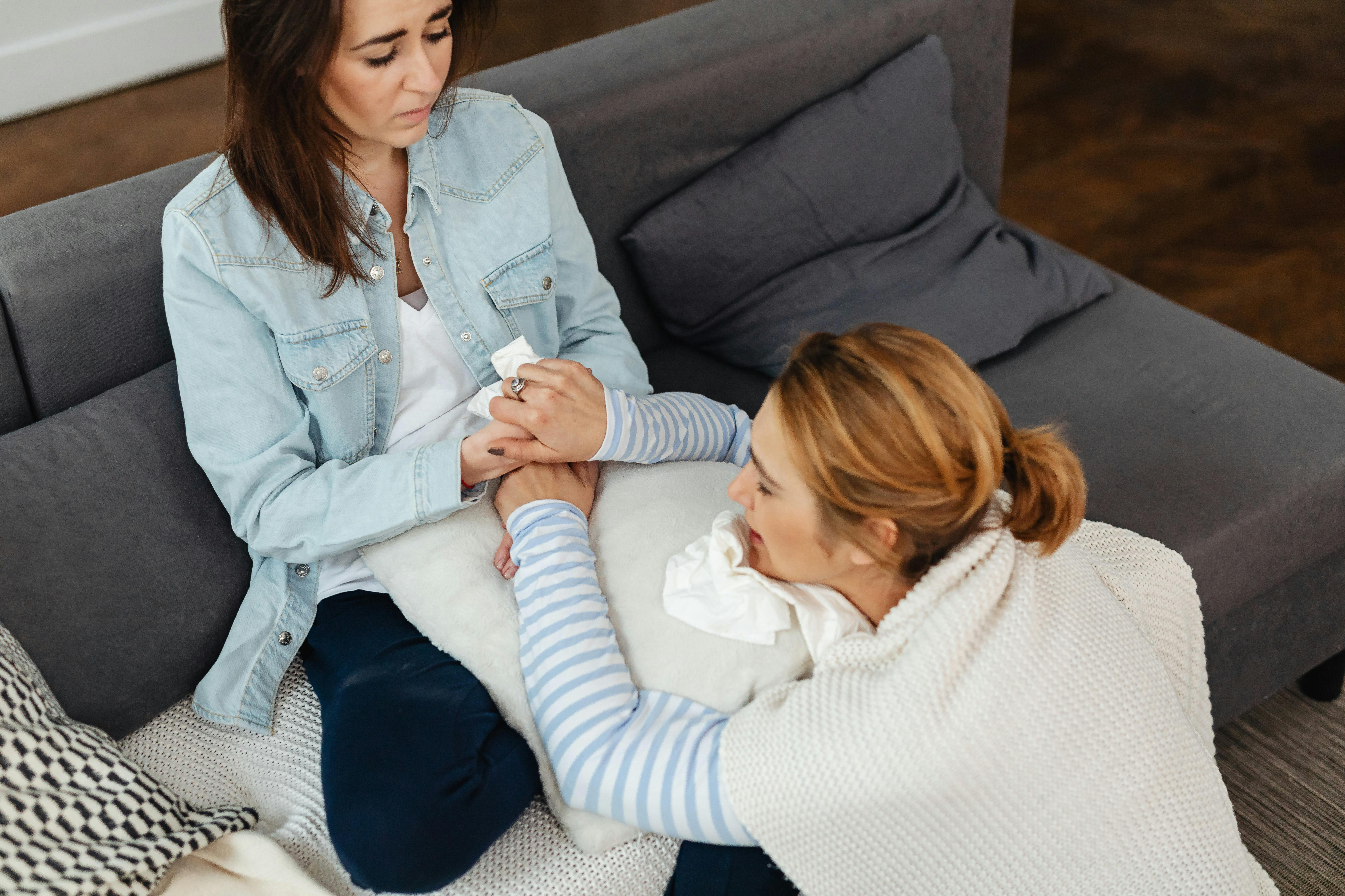 woman in a denim jacket holding hands with a crying woman