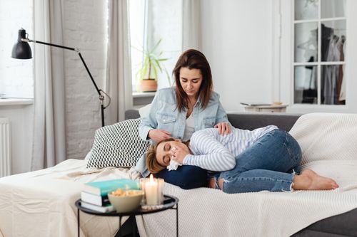 Free Two women sitting on a couch, with one comforting the other in an emotional moment. Stock Photo