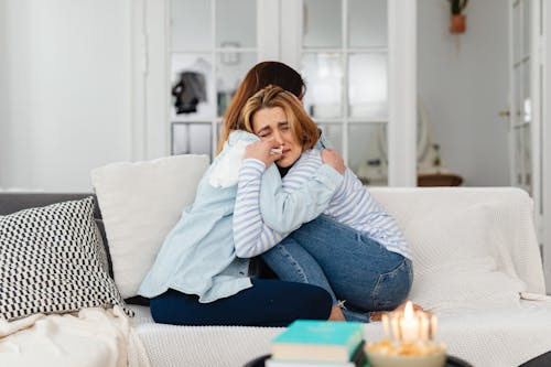 Free Sad Women Hugging on a Couch Stock Photo