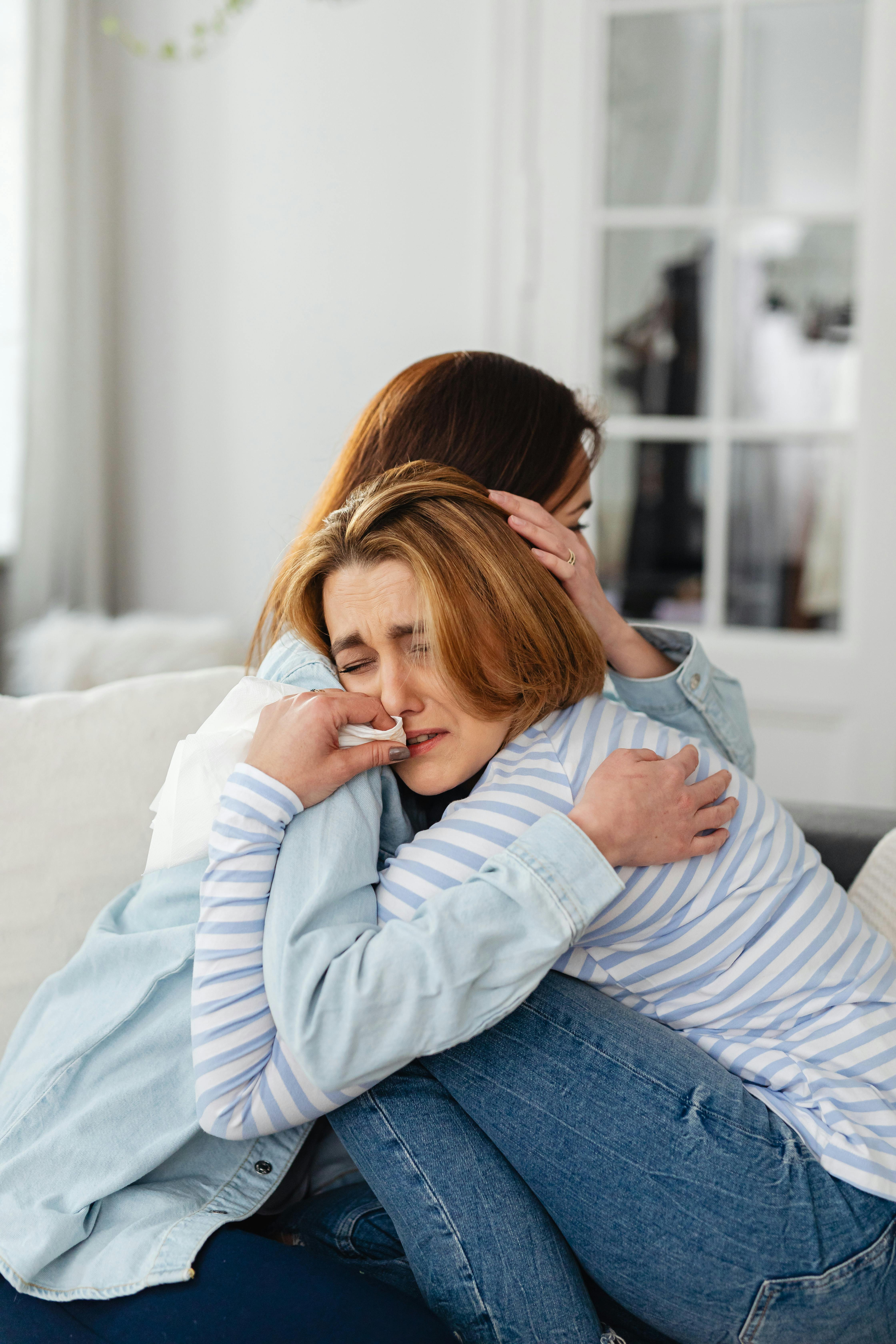 photo of a woman hugging a sad woman