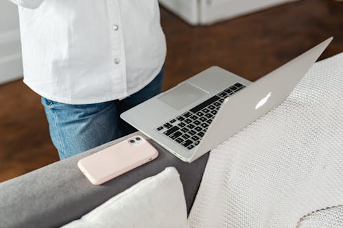 Photo of a Laptop Beside a Phone with a Pink Case