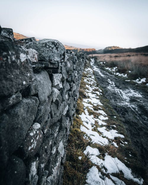 Stone Wall Stretching Along Muddy Road in Winter